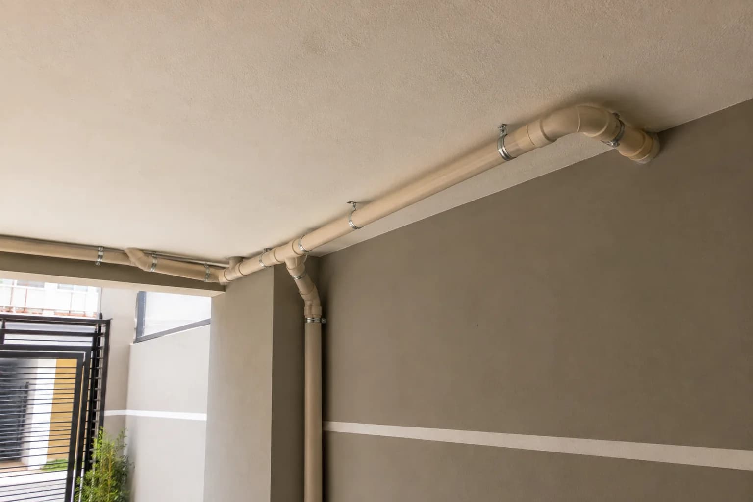 Tubos de esgoto fixados por cintas metálicas no teto de garagem